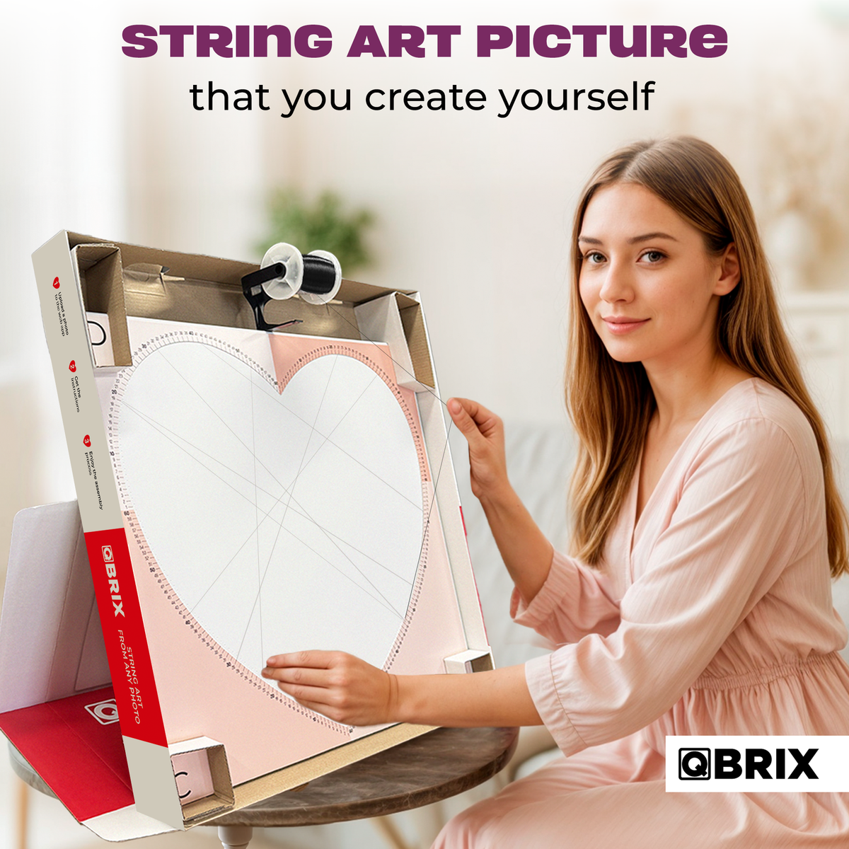 Woman displaying a QBRIX heart-shaped string art picture in a wooden frame