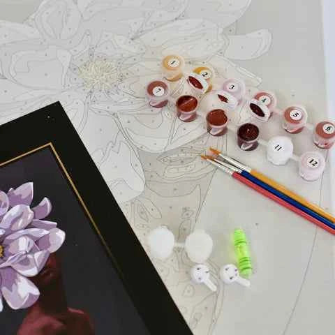 Art supplies including paint pots, brushes, and a partially completed artwork on a table.