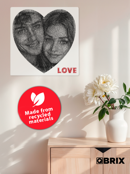 Heart-shaped artwork of two faces with 'LOVE' text, QBrix branding, and recycled materials label on a light background.