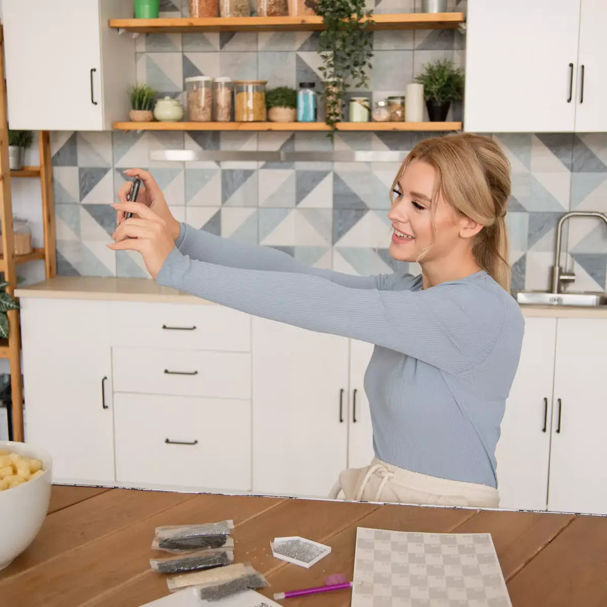 Woman taking a selfie in a kitchen with geometric tile backsplash